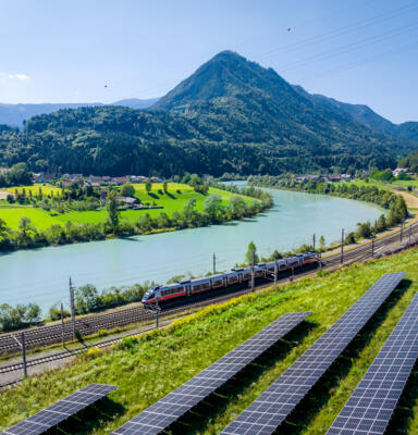 Standortmarketing_Photovoltaikļ23_615-original Personenzug fährt entlang eines Flusses durch eine grüne Tallandschaft